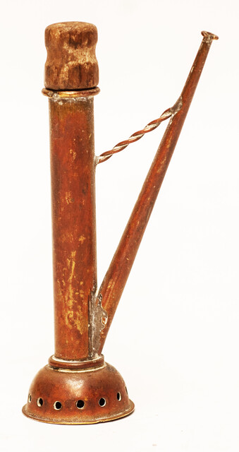 A copper toy window spout with a wooden stamper.