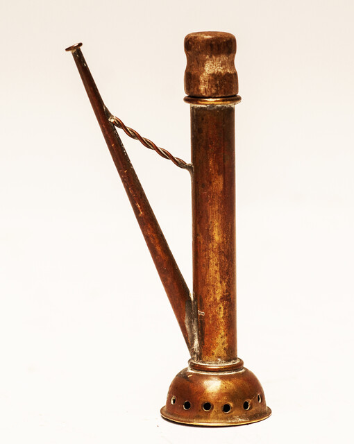 A copper toy window spout with a wooden stamper.