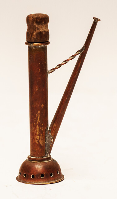 A copper toy window spout with a wooden stamper.