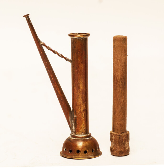 A copper toy window spout with a wooden stamper.