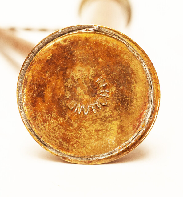 A copper toy window spout with a wooden stamper.