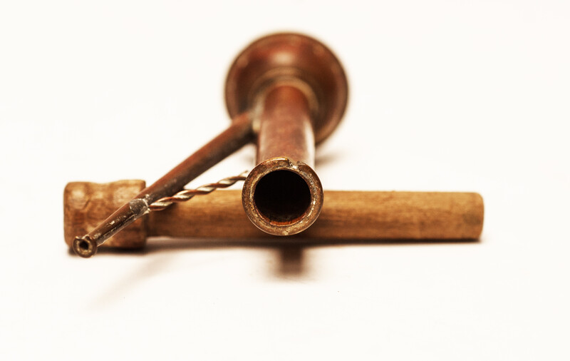 A copper toy window spout with a wooden stamper.