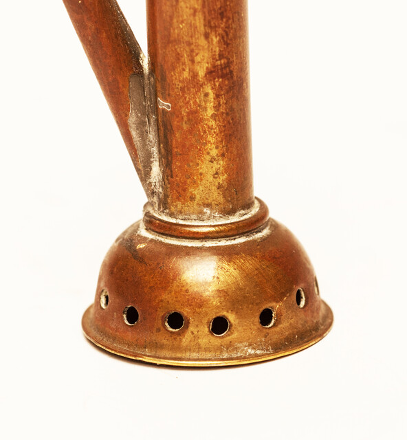 A copper toy window spout with a wooden stamper.