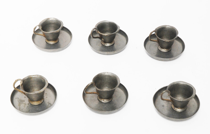 A pewter toy tea service consisting of six cup and saucers.