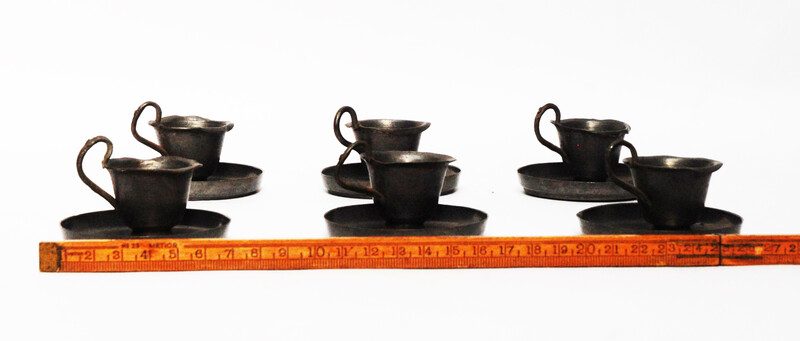 A pewter toy tea service consisting of six cup and saucers.