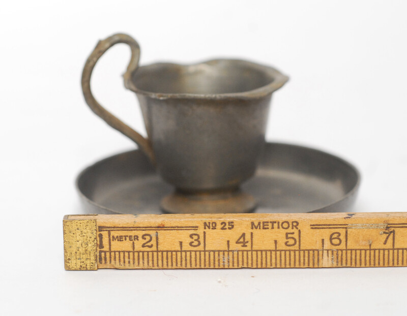 A pewter toy tea service consisting of six cup and saucers.