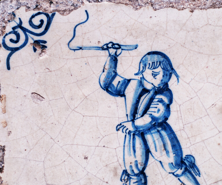 A rare early seventeenth century Delft blue tile with a boy whipping a top.