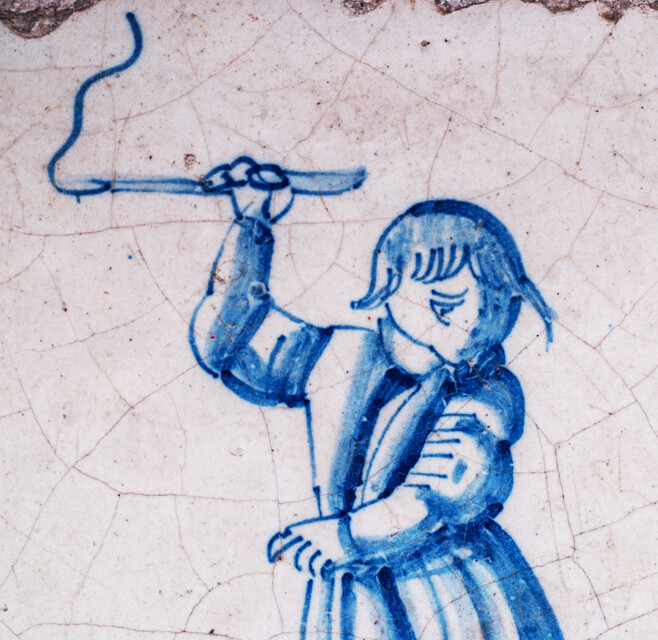 A rare early seventeenth century Delft blue tile with a boy whipping a top.