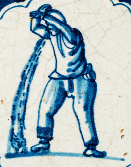 A rare early seventeenth century Delft blue tile with a vomiting man and Wanli corner decorations.