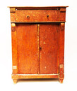 A red painted childrens cabinet with two doors and a drawer.