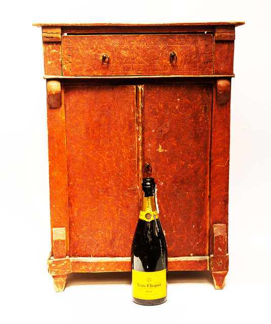 A red painted childrens cabinet with two doors and a drawer.