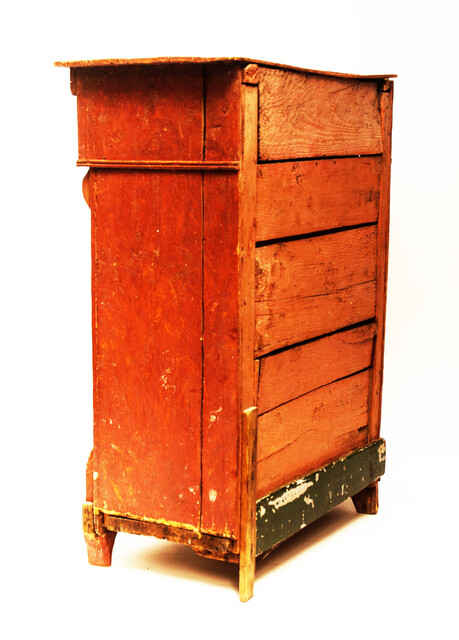 A red painted childrens cabinet with two doors and a drawer.