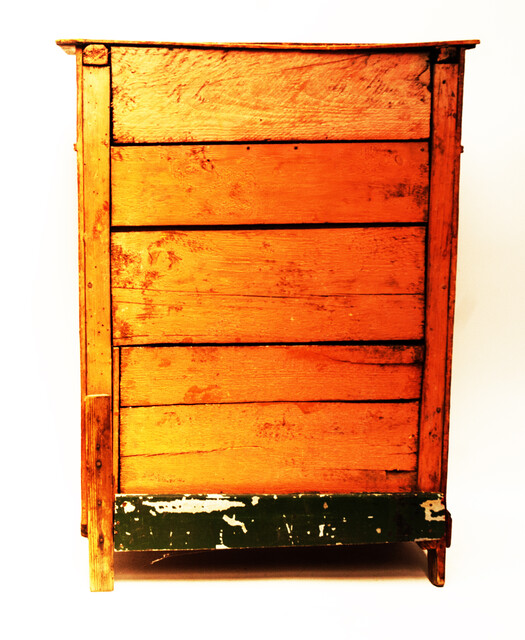 A red painted childrens cabinet with two doors and a drawer.