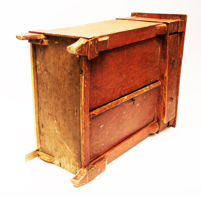 A red painted childrens cabinet with two doors and a drawer.