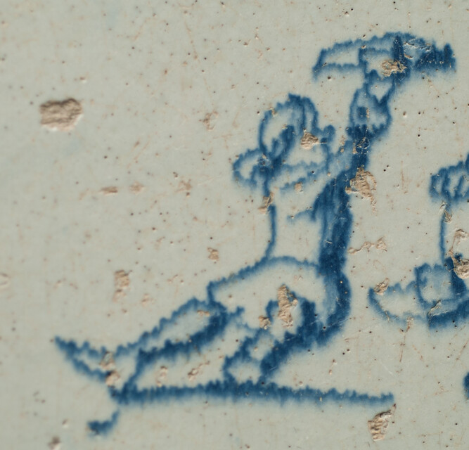 A seventeenth century Delft blue tile with two boys playing with their hats.