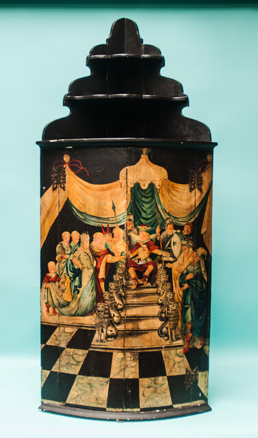 An 18th C. hanging corner cabinet from Ameland painted with a scene of King Solomon on his lion throne.