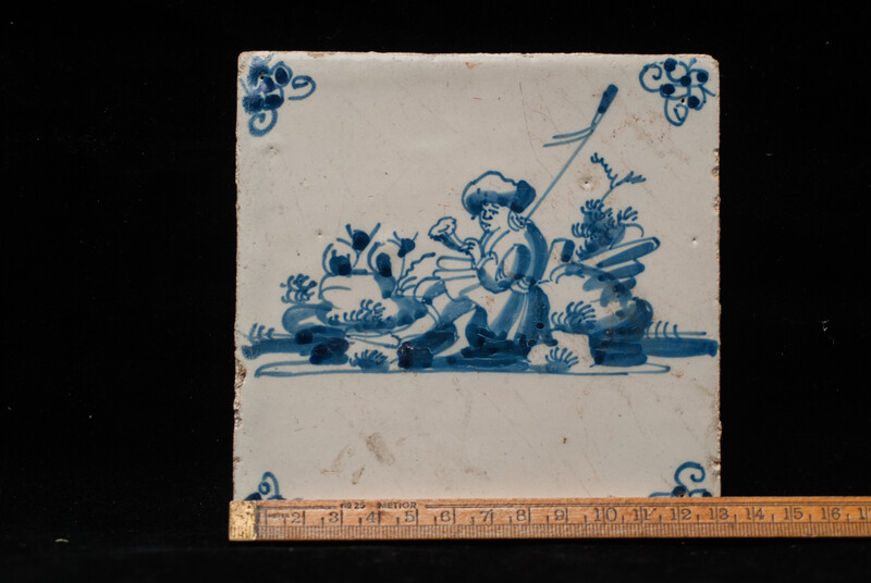 An 18th century Delft blue tile of a shepherd playing a shawm.